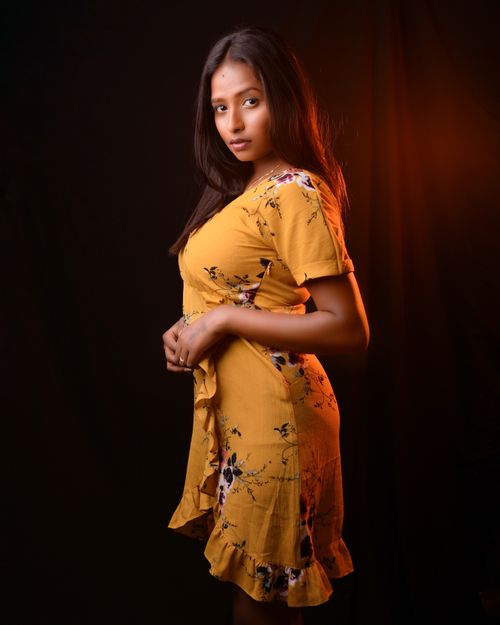 Free Stunning portrait of a woman in a floral yellow dress, captured in a dramatic studio setting. Stock Photo