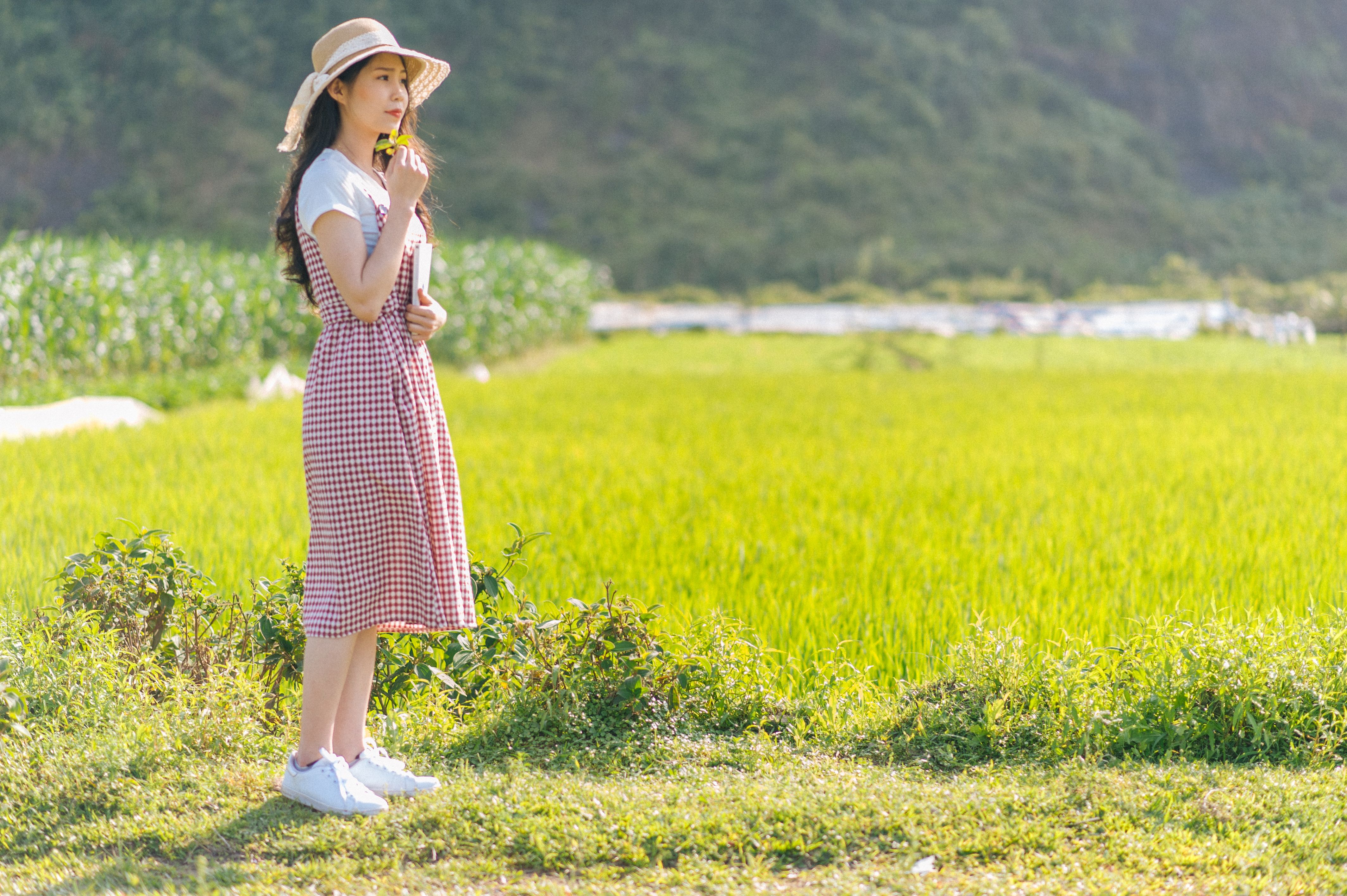 Photo of a Woman with a Hat Standing on Green Grass · Free Stock Photo
