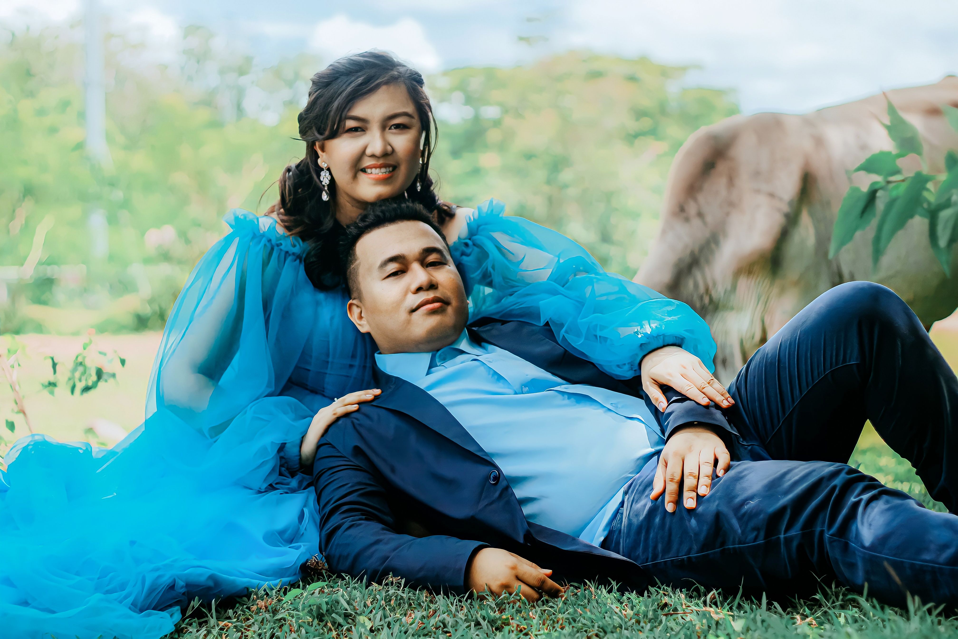 Happy couple in elegant attire enjoying a relaxing moment outdoors, embracing love.