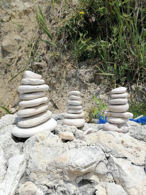 Free Artistic balance of stacked stones on a rocky surface, surrounded by natural greenery. Stock Photo