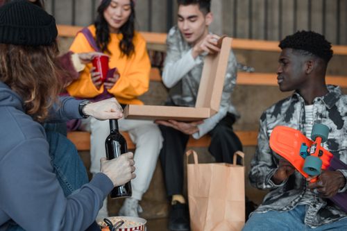 Free Group of diverse friends enjoying pizza and drinks indoors with a skateboard. Stock Photo