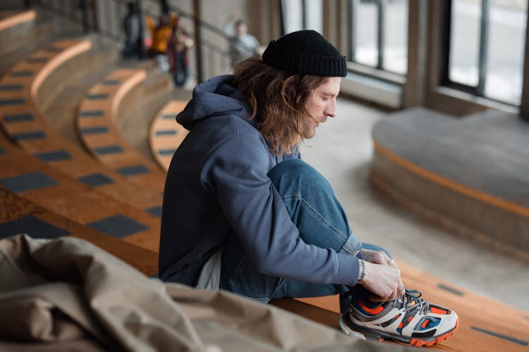 Photo Of A Man In A Hoodie Tying His Shoelaces