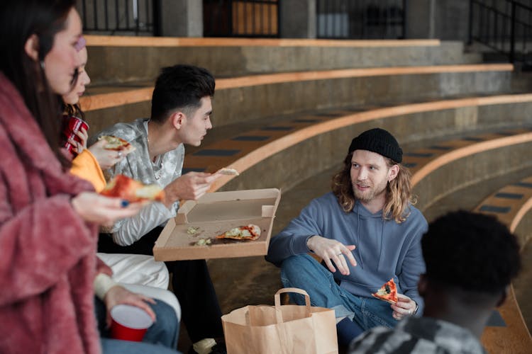Photo Of A Group Of Friends Talking While Eating Pizza