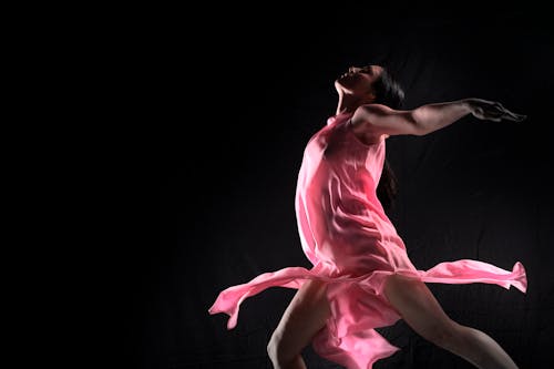 A Woman in Pink Dress Dancing Gracefully