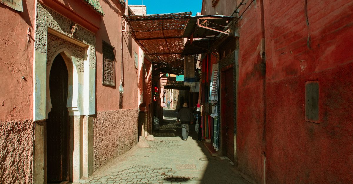 Narrow Moroccan alleyway with red buildings and a cobblestone path creating an atmospheric scene.