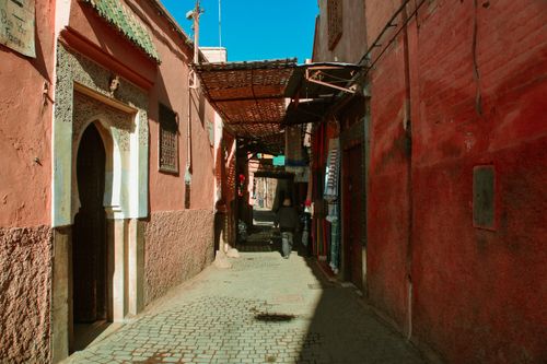 Free Narrow Moroccan alleyway with red buildings and a cobblestone path creating an atmospheric scene. Stock Photo