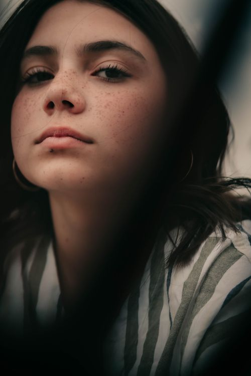 Free Artistic close-up portrait of a young woman with freckles, showcasing natural beauty. Stock Photo