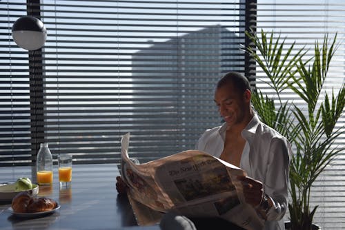 Free Photo of a Man Reading a Newspaper while Smiling Stock Photo