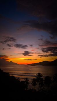 Beautiful tropical sunset with palm trees silhouetted against a vibrant sky over a serene sea.