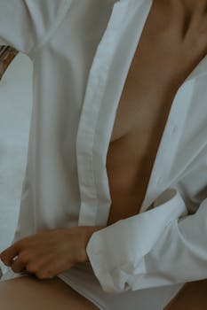 Sensual close-up of a woman in an unbuttoned white shirt, creating a minimalistic and artistic mood.