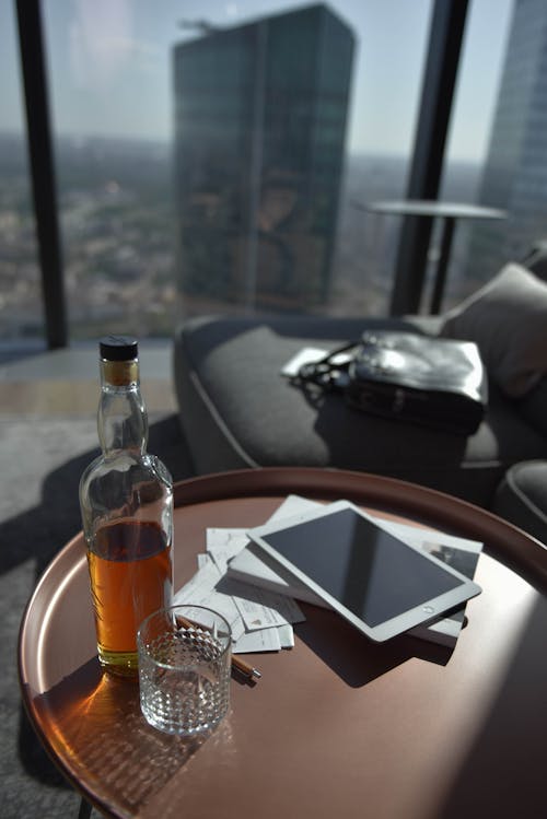 A Bottle of Whiskey and Glass Cup on Coffee Table