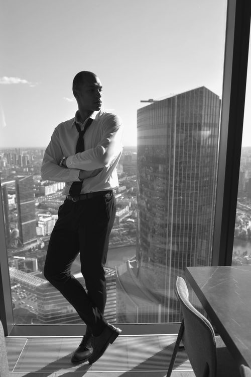 Free Monochrome image of a businessman leaning in a skyscraper overlooking a cityscape. Stock Photo