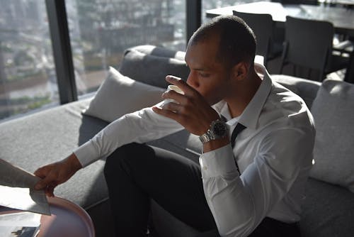 Photo of a Man in a White Dress Shirt Drinking Coffee
