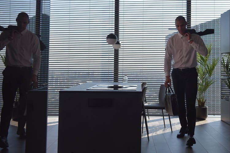 A Man Walking Inside His Home Carrying A Briefcase