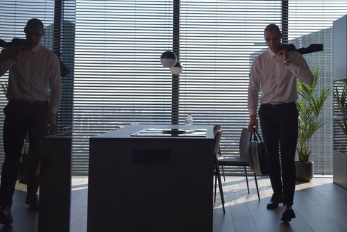 Free Businessman with briefcase in a modern office with window blinds and plants. Stock Photo