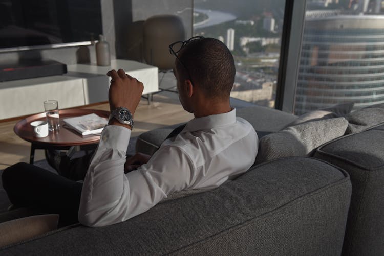 A Man In White Long Sleeves Sitting On The Couch