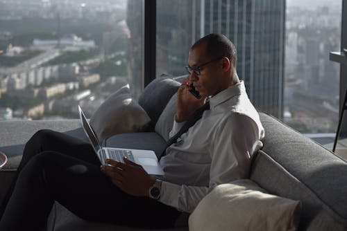 Man Using Laptop While on a Phone Call