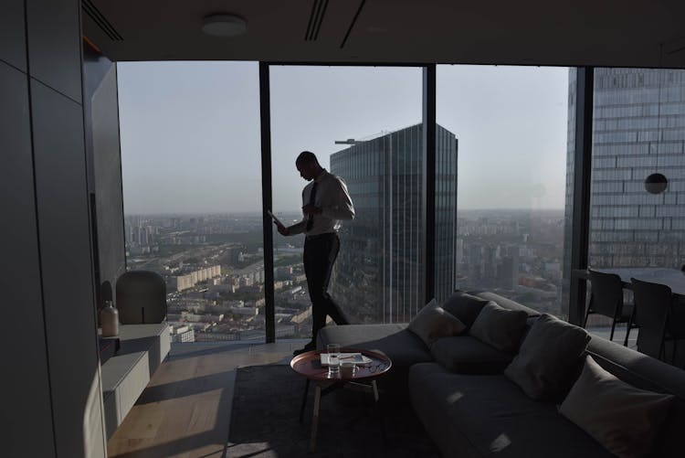 Man In Luxury Apartment With Skyscraper And City Buildings Behind