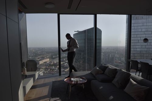 Free Silhouette of a businessman standing in a luxury apartment with a panoramic cityscape view. Stock Photo
