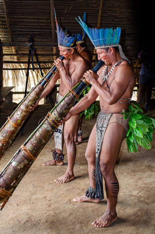 Men in Tribal Hats Blowing Musical Instruments