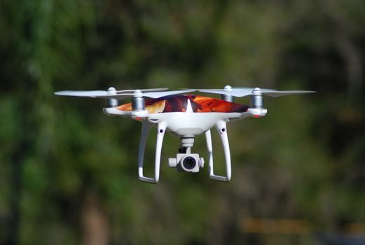 Close-up image of a drone hovering in the air with a blurred nature background.