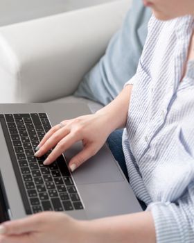 Person typing on a laptop keyboard with focus on the hands, showcasing tech use.