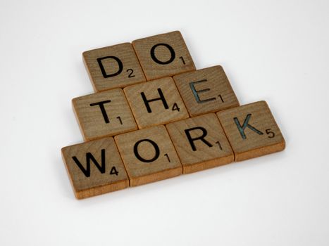 Creative arrangement of Scrabble tiles spelling 'Do the Work' on a white background.