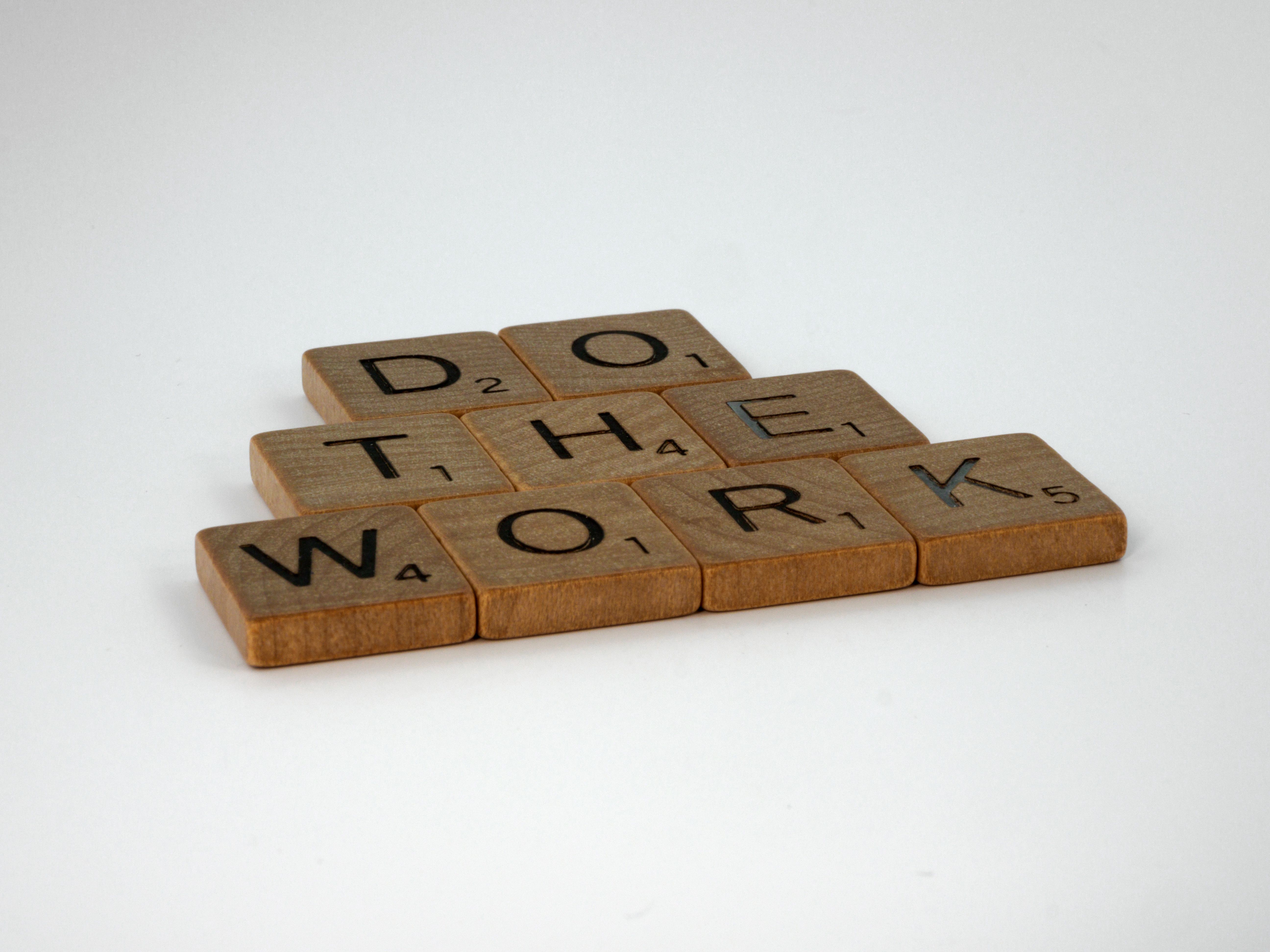 Motivational message spelled out with scrabble tiles on white background.