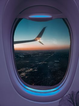 A stunning aerial view of Denver beneath a sunset sky, framed by an airplane window.