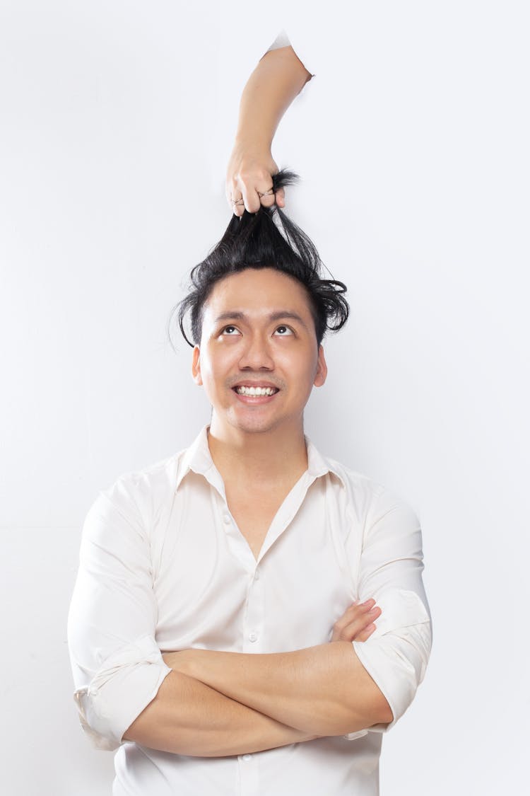 A Man In White Long Sleeves Looking Up On A Hand Pulling His Hair