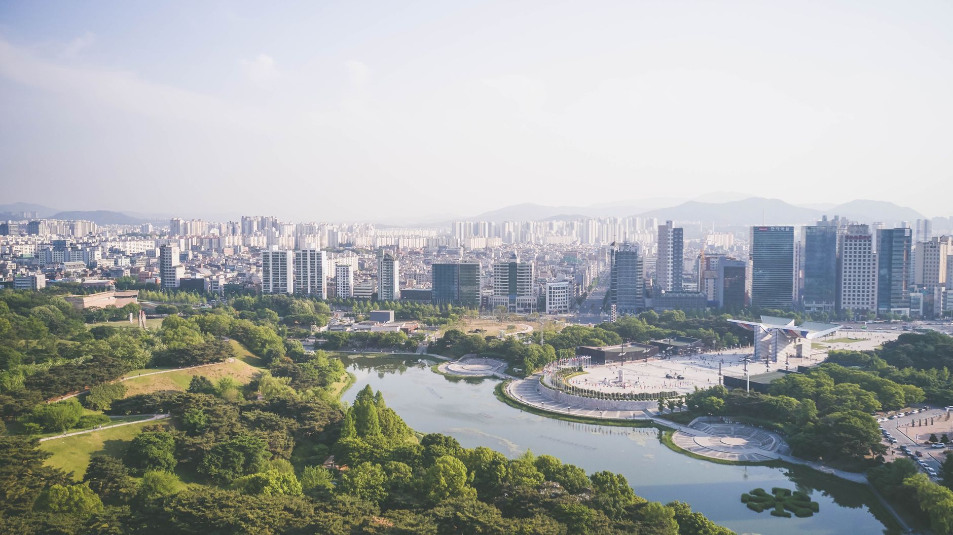Aerial view of a lush park and bustling cityscape with modern skyscrapers.