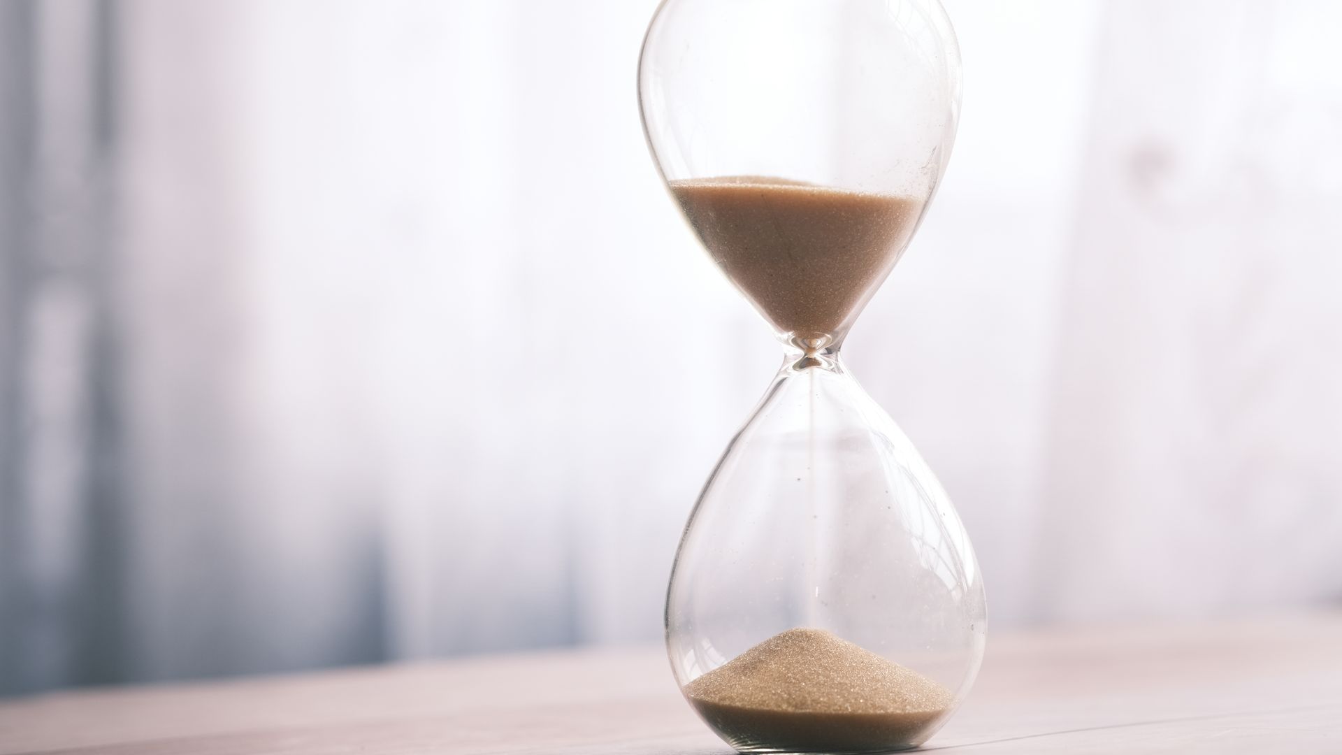 Modafinil Duration: How Long Does It Last? Minimalist hourglass filled with sand symbolizing time and patience, against a soft background.