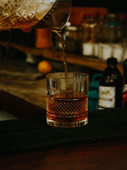 Free A close-up shot of whiskey being poured into a textured glass, capturing the golden hues and ambiance of a bar. Stock Photo