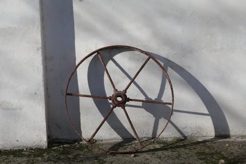 Rusty Wheel Beside White Wall