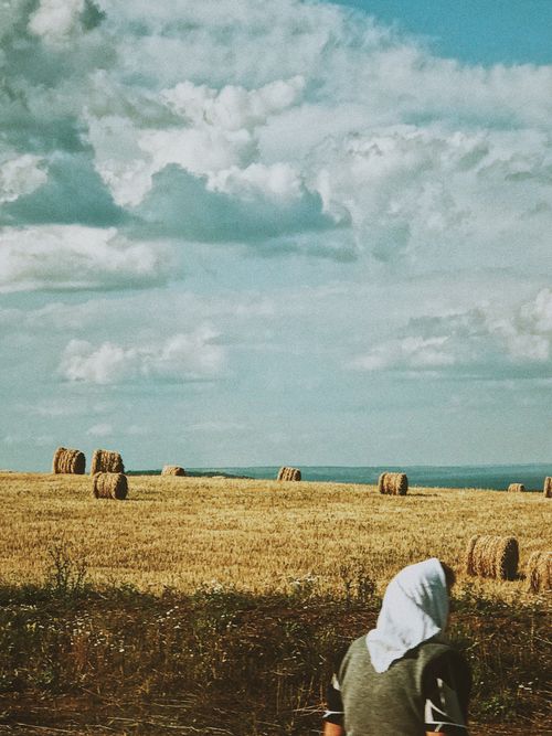 Free Rural landscape with hay bales and a woman in a headscarf on a summer day. Stock Photo