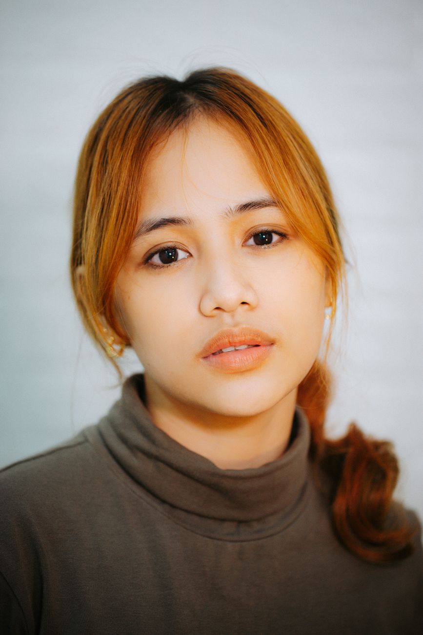 Close-up portrait of a young Asian woman with light makeup and a turtleneck.