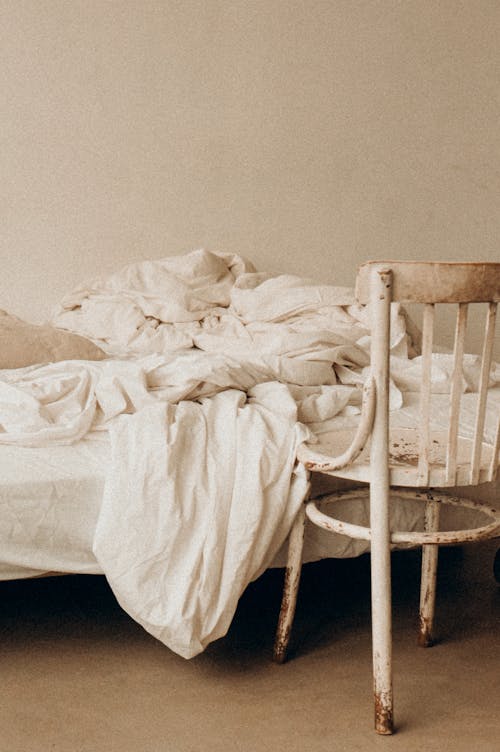 White Chair Beside Bed with White Blanket