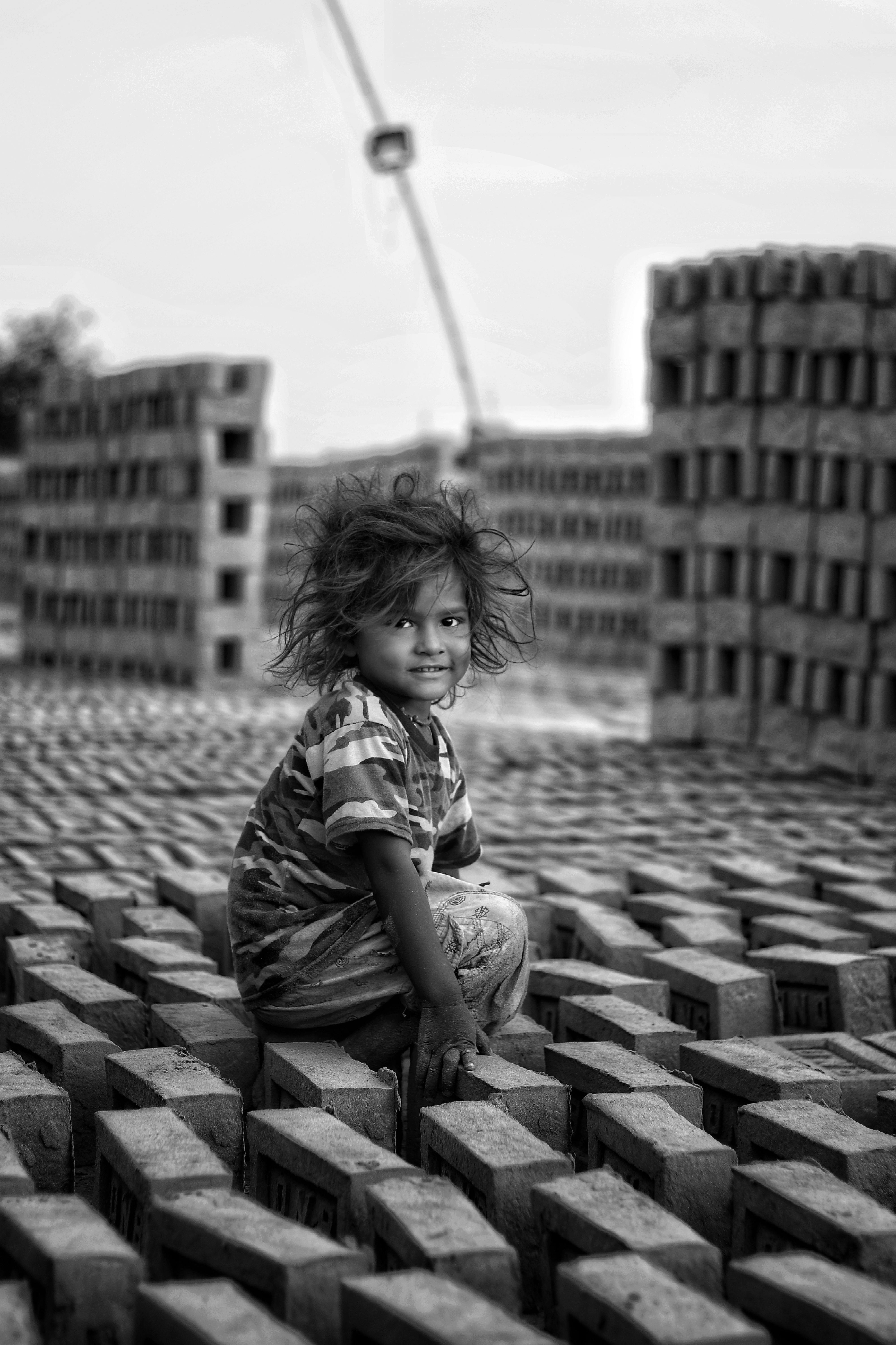 child sitting on bricks on construction site