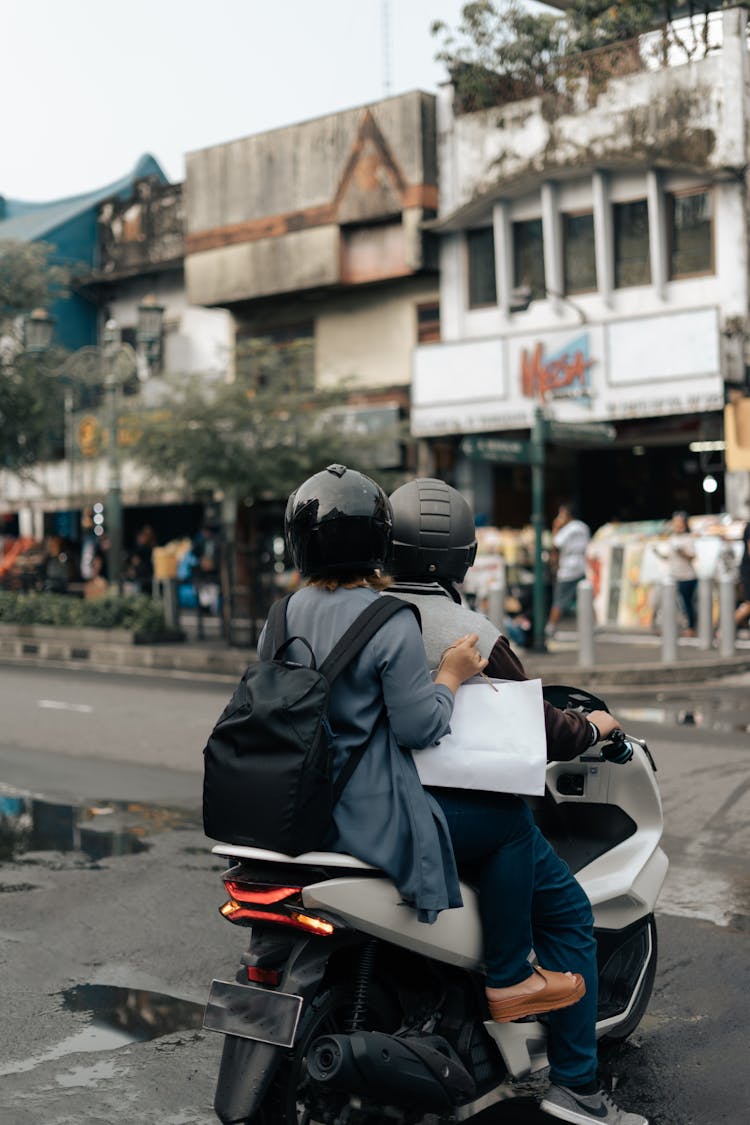 A Couple Riding A Scooter