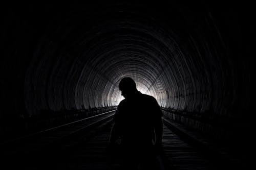 Silhouette of Man Walking on Tunnel