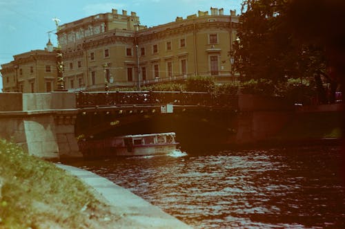 Boat Swimming Under the Bridge Beside Old Building