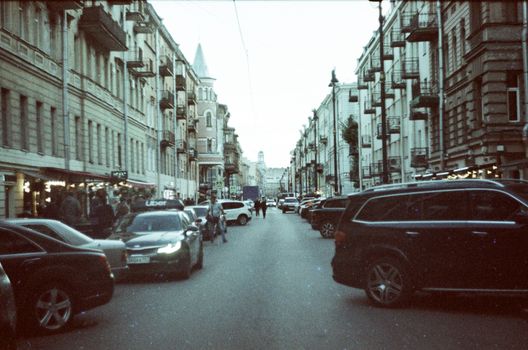 A bustling city street lined with historic buildings and cars during dusk.
