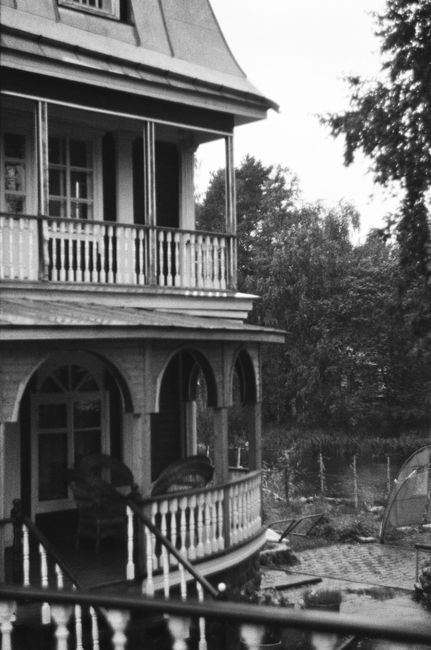 A classic grayscale image of a historic house showcasing its facade, balcony, and porch.