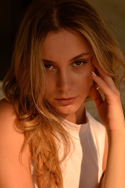Free Portrait of a young woman with contemplative gaze and soft lighting, exuding elegance and warmth. Stock Photo