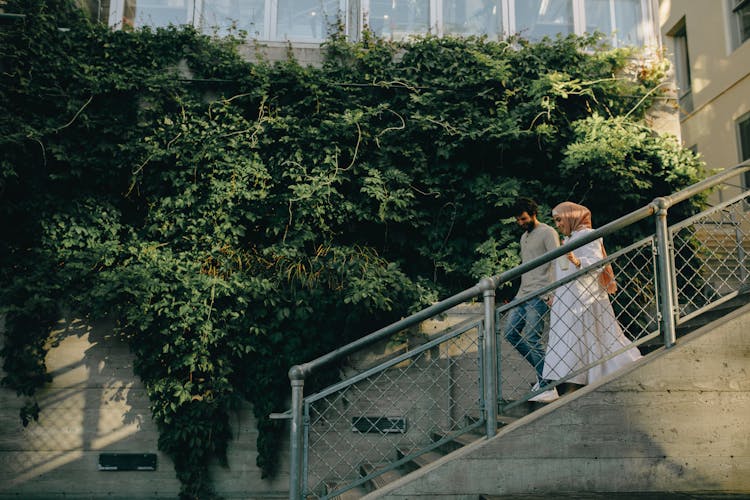 A Man And Woman Walking Down The Stairs While Having Conversation