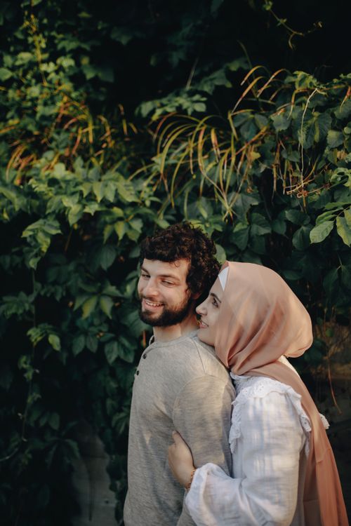 Free A happy couple shares an intimate embrace outdoors surrounded by lush greenery. Stock Photo