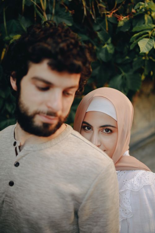Free A beautiful couple, one wearing a hijab, standing closely together outdoors. Stock Photo
