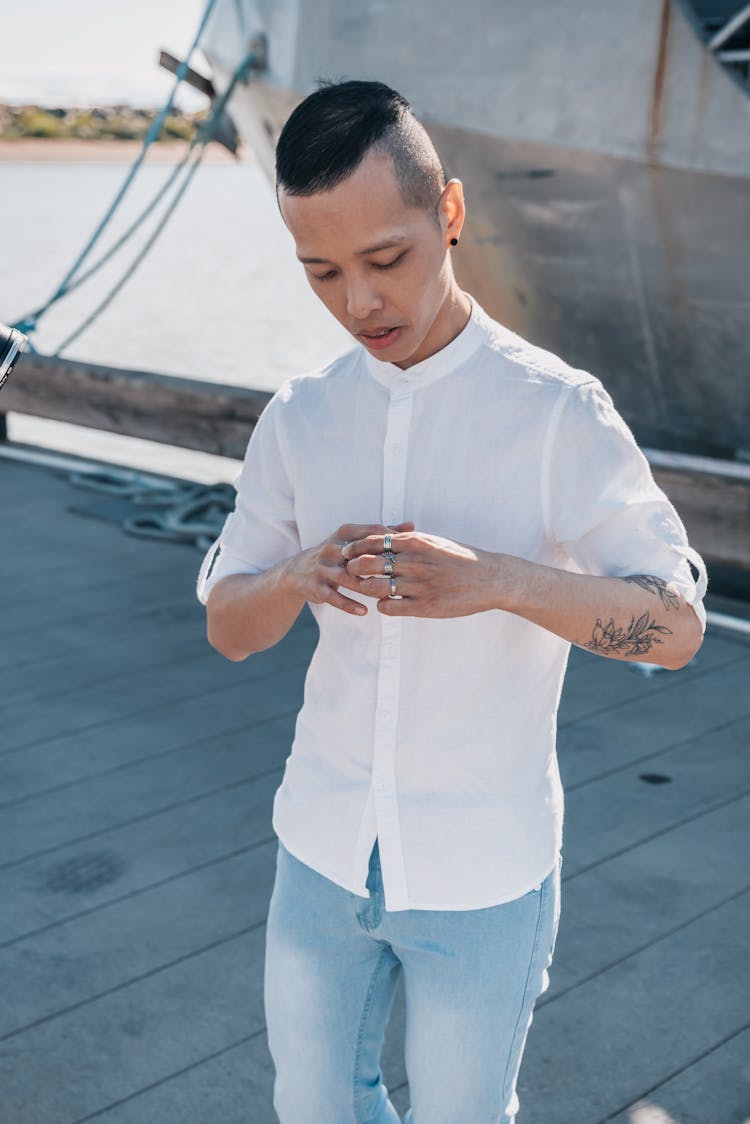 Tattooed Man In White Polo Wearing Rings