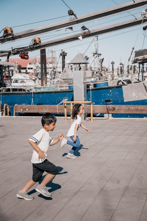 Free Boy and Girl Running Together at a Wooden Dock Stock Photo