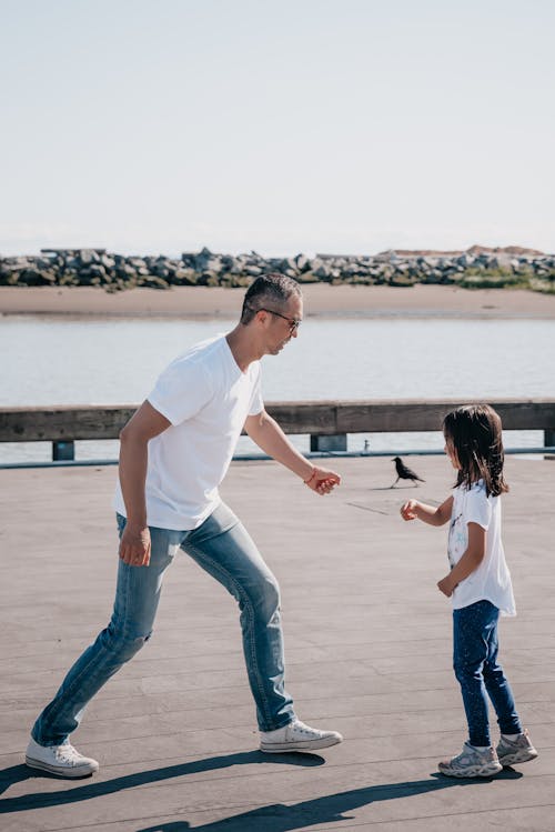 Free Dad and Daughter Playing Together on Wooden Dock Stock Photo